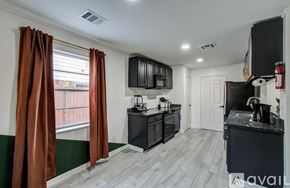 Houston house for rent - A kitchen with black cabinets and a black countertop with a white door in the background.
