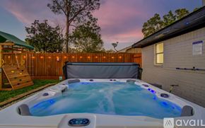 Houston house for rent - A hot tub is in the backyard with a wooden fence and a slide.