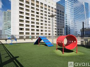 Jersey City apartment for rent - A playground with a red tunnel and a blue slide in front of a white building.