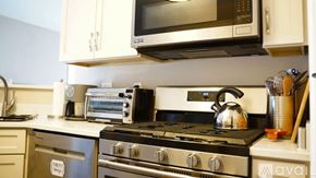 Crown Point apartment for rent - A modern kitchen with a stove top oven and microwave above it.