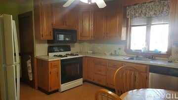 Norwood apartment for rent - A kitchen with wooden cabinets and a white refrigerator.