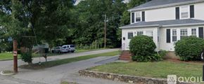 Norwood apartment for rent - A house with a white exterior and a grey roof is situated on a street with a car parked in front.