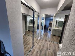 San Diego apartment for rent - A person is standing in a room with a mirrored wall and wooden flooring.