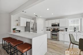 Flower Mound house for rent - A modern kitchen with white cabinets and a marble island.