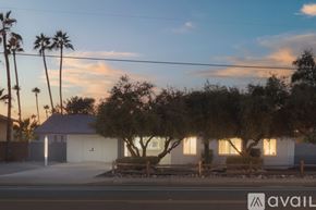 Scottsdale house for rent - A house with a white exterior and a brown roof is surrounded by trees and palm trees.