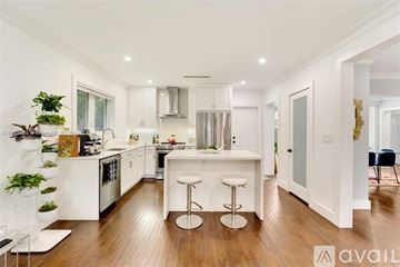 Coral Gables house for rent - A modern kitchen with white cabinets and a wooden floor.