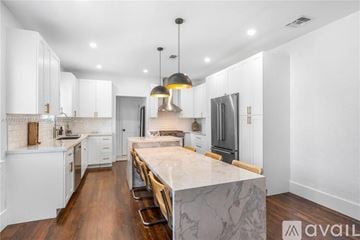 Miami house for rent - A modern kitchen with white cabinets and a central island.
