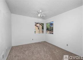 Moreno Valley apartment for rent - A room with a carpeted floor, a ceiling fan, and a window showing a view of a building.