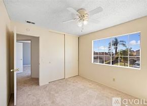 Moreno Valley apartment for rent - A room with a ceiling fan and a window showing a view of a residential area.