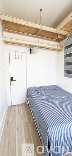 Brooklyn apartment for rent - A room with a bed, a window with red curtains, and posters on the wall.