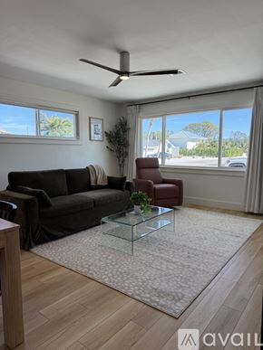 Venice apartment for rent - A living room with a black couch, a glass coffee table, and a ceiling fan.