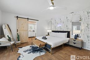 Haltom City house for rent - A bedroom with a bed, dresser, and mirror with a white and black patterned wallpaper.