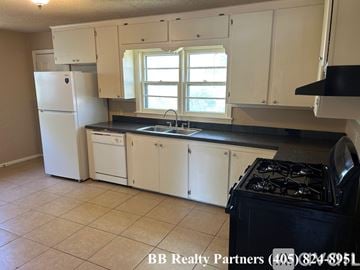 Tulsa apartment for rent - A kitchen with white cabinets and a black stove top.