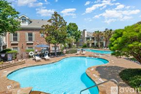 Carrollton apartment for rent - A swimming pool surrounded by trees and chairs with a building in the background.