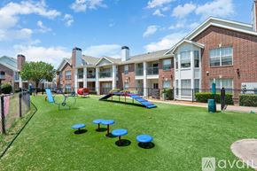 Carrollton apartment for rent - A playground area with a slide, swings, and tables in front of apartment buildings.