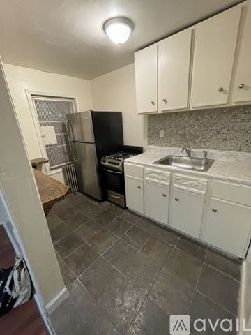 Brooklyn townhouse for rent - A kitchen with white cabinets and a black fridge.