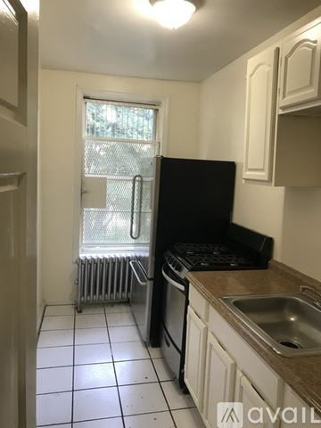 Brooklyn townhouse for rent - A kitchen with black appliances and white cabinets.