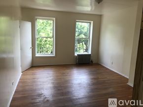 Brooklyn townhouse for rent - A room with wooden floors and two windows.