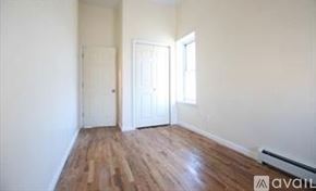Brooklyn townhouse for rent - A room with wooden floors and white walls, with a door on the left and a window on the right.