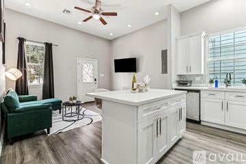 New Orleans house for rent - A modern kitchen with white cabinets and a green chair.