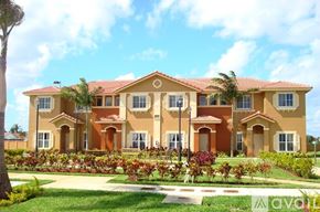 Hialeah townhouse for rent - A large, multi-story house with a red tile roof and a well-manicured lawn in front.