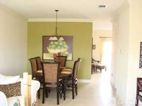 Hialeah townhouse for rent - A dining room with a green wall and a painting of a bowl of fruit.