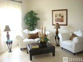 Hialeah townhouse for rent - A living room with a white couch, a glass table, and a potted plant.