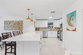 Miami house for rent - A kitchen with white cabinets and a marble island.