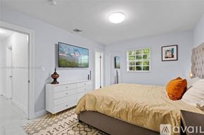 Miami house for rent - A bedroom with a bed, dresser, and television.