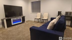 Idaho Falls house for rent - A living room with a blue couch, a television, and two chairs.
