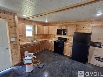 Caddo house for rent - A kitchen area with wooden cabinets and a black refrigerator.