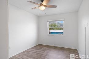 St. Pete Beach apartment for rent - A room with a ceiling fan and a window overlooking a pool.