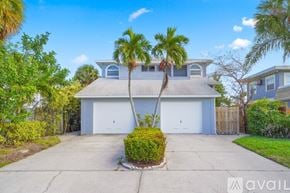 St. Pete Beach apartment for rent - A house with a driveway and two palm trees in front.