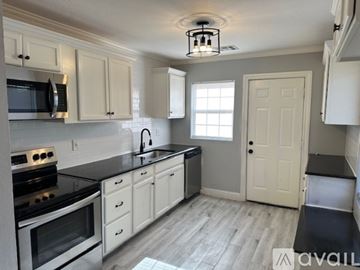 Oklahoma City house for rent - A kitchen with white cabinets and black countertops.