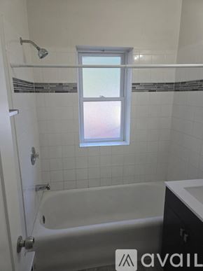Chicago apartment for rent - A white bathroom with a tub and a window.
