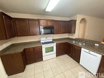 San Antonio house for rent - A kitchen with brown cabinets and white appliances.