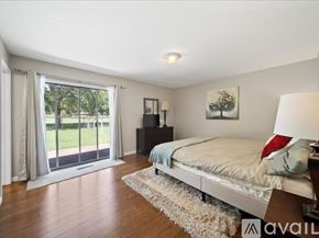 Broken Arrow house for rent - A bedroom with a large bed and a sliding glass door leading to a garden.