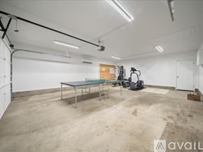 Broken Arrow house for rent - A spacious garage with a table and chairs in the middle.