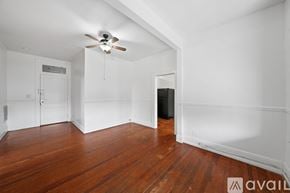 Tampa apartment for rent - A room with wooden floors and white walls, a ceiling fan, and a door leading to another room.
