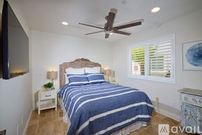 Oceanside apartment for rent - A bedroom with a bed, a ceiling fan, and a nightstand with a plant on it.