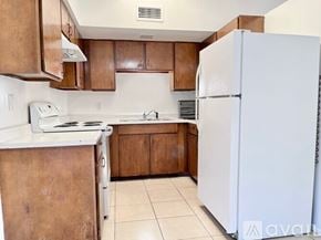 Phoenix apartment for rent - A kitchen with brown cabinets and a white refrigerator.