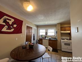 Boston apartment for rent - A kitchen with a table and chairs in front of a wall with a banner on it.