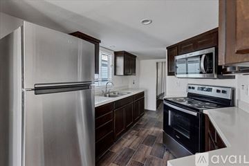 Barstow apartment for rent - A modern kitchen with a stainless steel refrigerator and dark wood cabinets.
