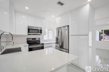 Miami house for rent - A modern kitchen with white cabinets and stainless steel appliances.