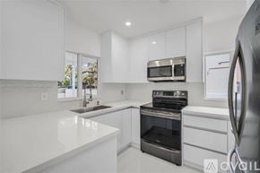 Miami house for rent - A modern kitchen with white cabinets and stainless steel appliances.
