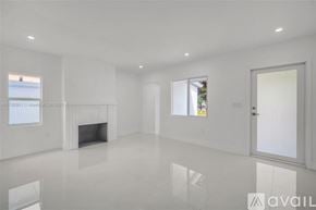 Miami house for rent - A spacious, white room with a fireplace and a large window.