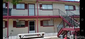 San Antonio apartment for rent - A building with a red and white facade and a black door.