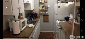 San Antonio apartment for rent - A kitchen with a white microwave, white fridge, and white cabinets.
