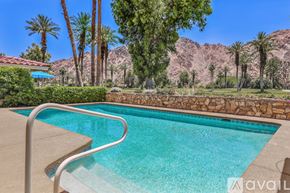 Indian Wells apartment for rent - A pool surrounded by palm trees and a mountain in the background.
