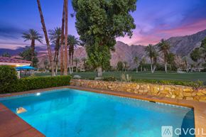 Indian Wells apartment for rent - A pool surrounded by palm trees and a mountain in the background.